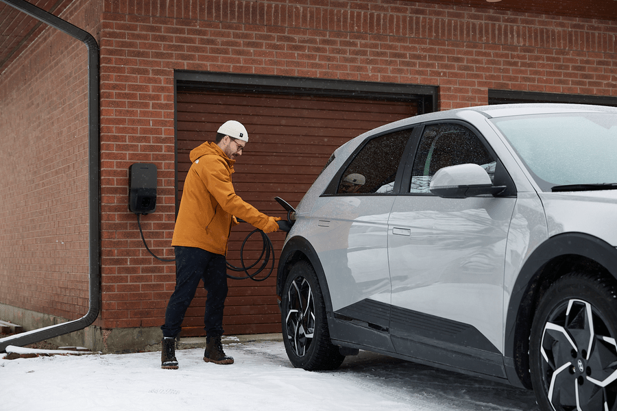 Flo Home Black X8 EV charging stations, installed outside of a house, men charging his EV during winter