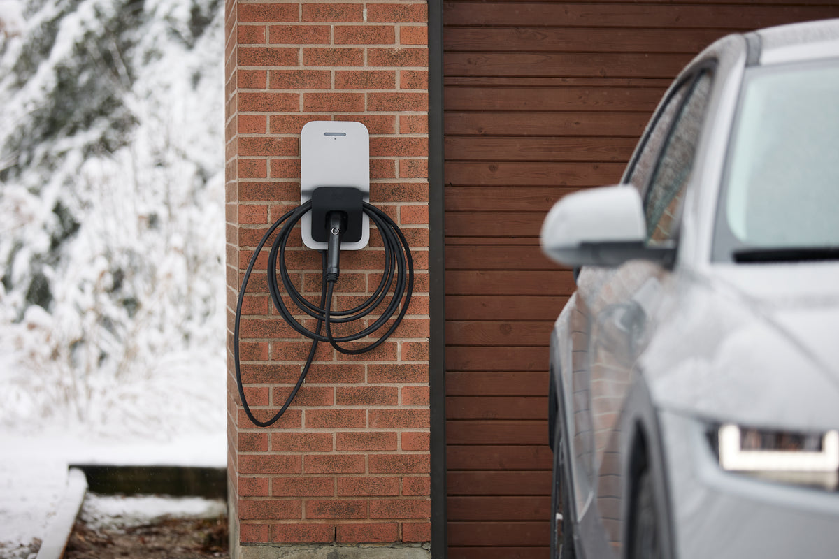Silver FLO Home X6 EV charger installed on the exterior wall of a home in winter