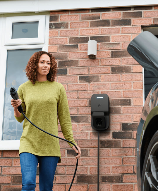 Flo Home Black X3 EV charging station, installed outside of home, woman charging an EV car