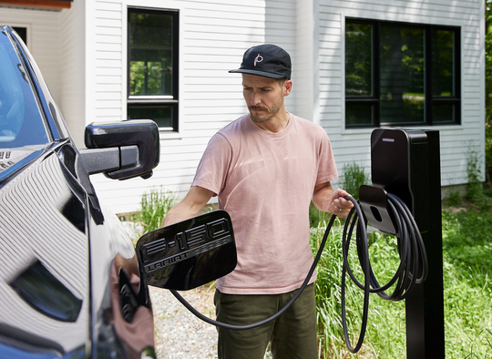 A man charging his EV pick up with Flos X8 Ev charging station mounted on a pedestal